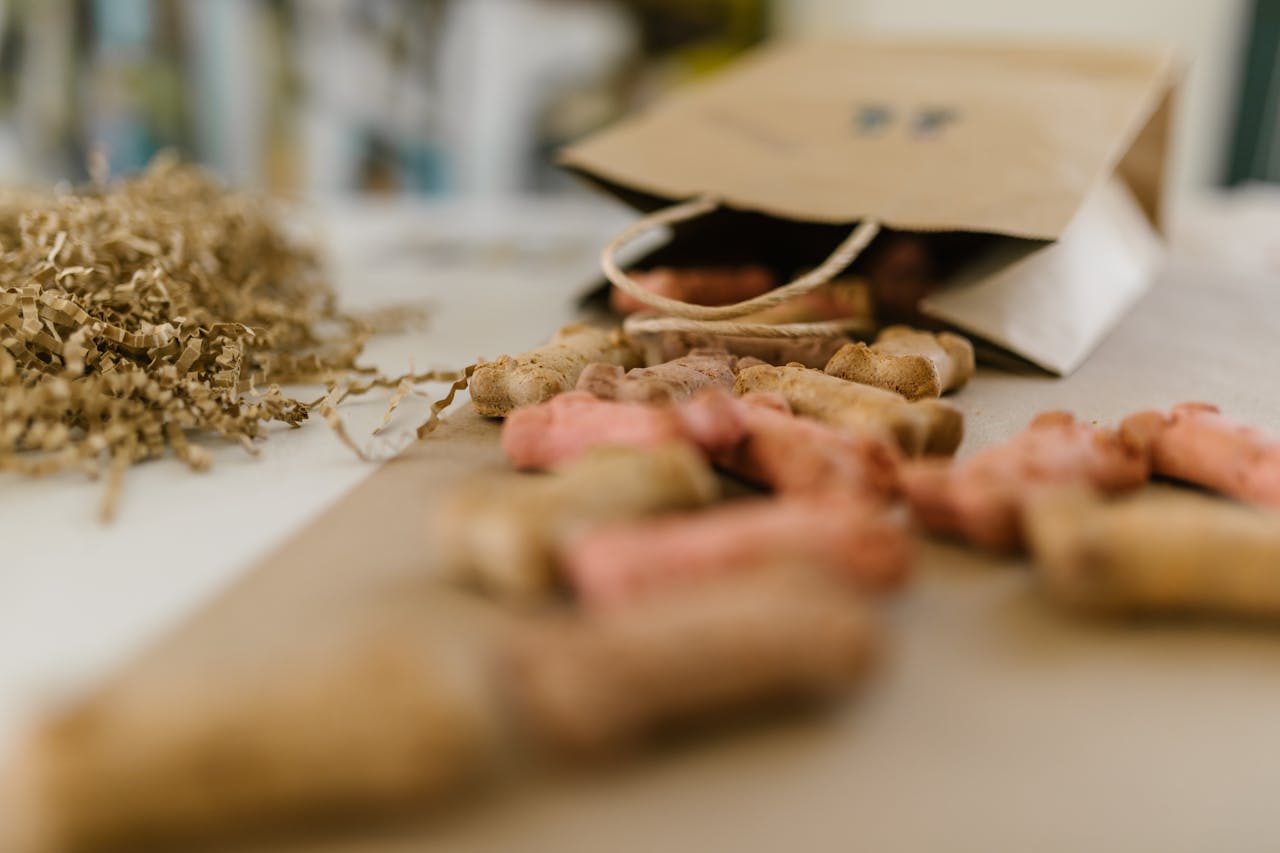 A paper bag spilling colorful dog treats amidst shredded confetti on a table.